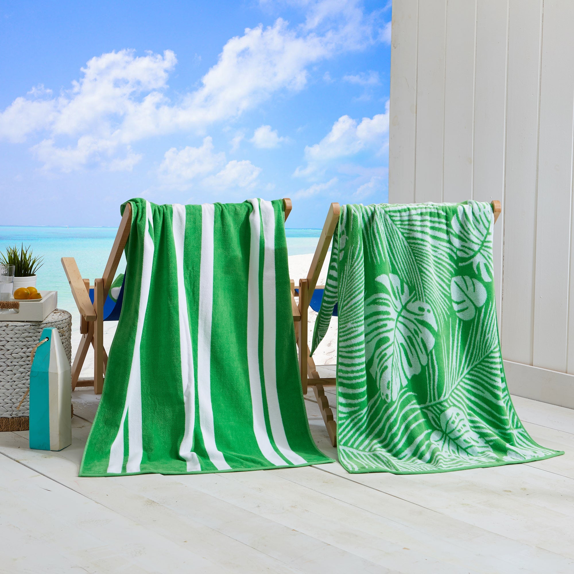 Maui Cotton Velour Beach Towel in vibrant green designs displayed on a chair by the beach.