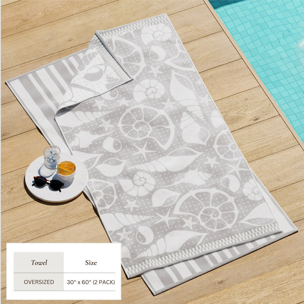Maui Cotton Velour Beach Towel in vibrant green designs displayed on a chair by the beach.