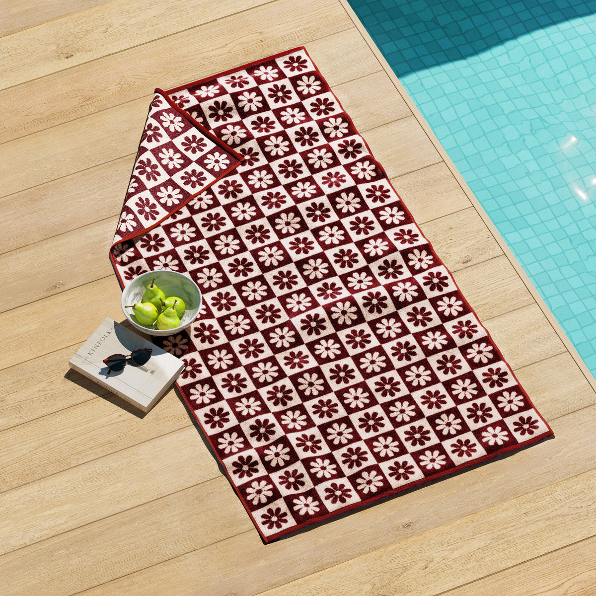 Maui Cotton Velour Beach Towel in vibrant green designs displayed on a chair by the beach.
