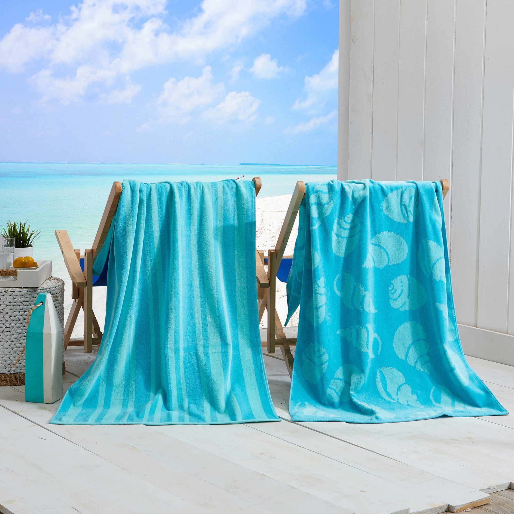 Maui Cotton Velour Beach Towel in vibrant green designs displayed on a chair by the beach.