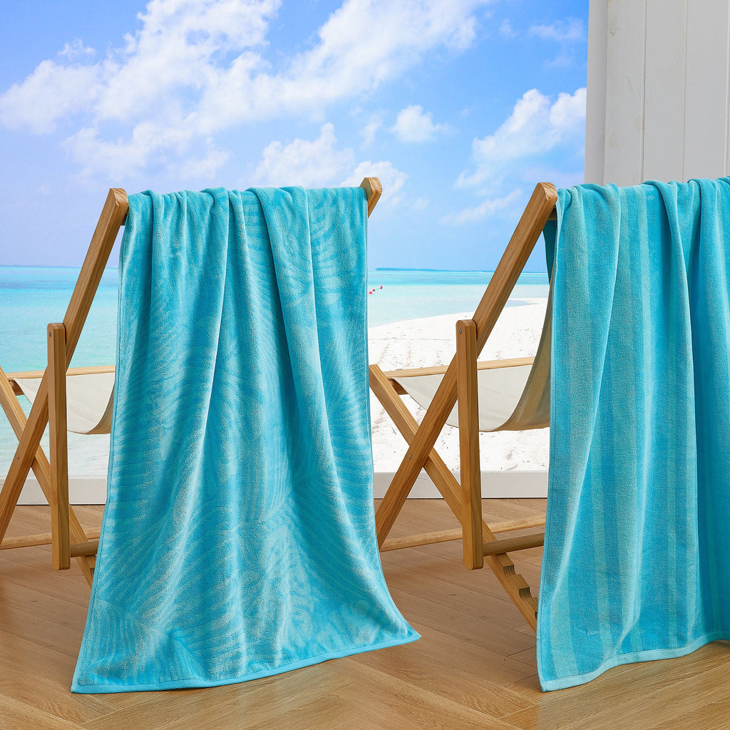 Maui Cotton Velour Beach Towel in vibrant green designs displayed on a chair by the beach.