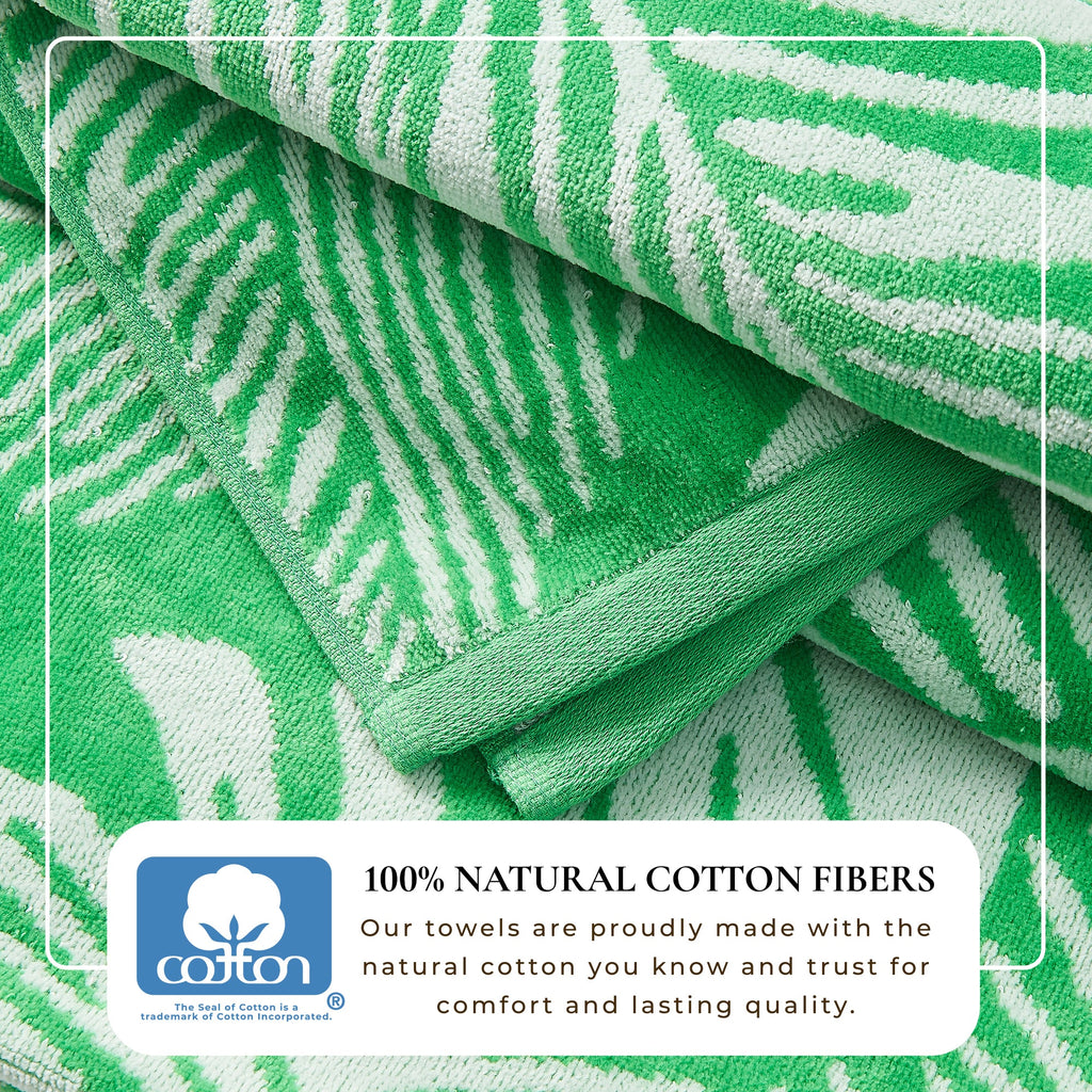 Maui Cotton Velour Beach Towel in vibrant green designs displayed on a chair by the beach.